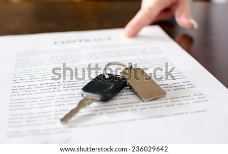 Car key on a signed sales contract, closeup