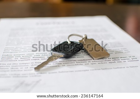Car key on a signed sales contract, closeup