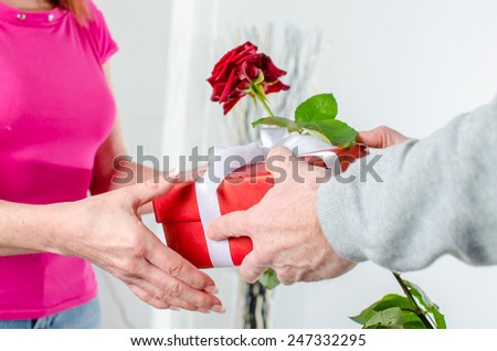 Man giving a rose and a gift to a woman for Valentine\'s day