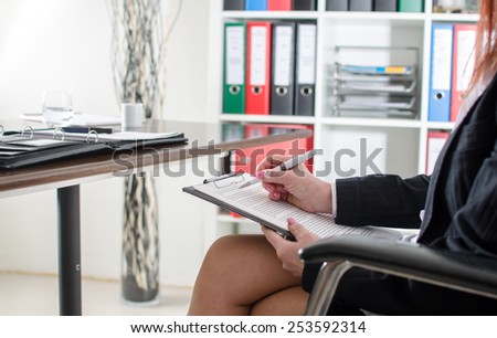Business woman taking notes on a clipboard