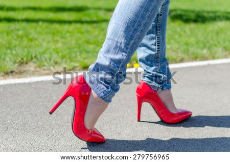 Fashioned woman wearing red high heel shoes walking in park