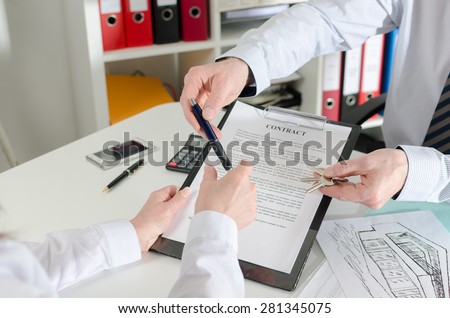 Realtor giving a pen to his client to sign the real estate contract in real estate agency