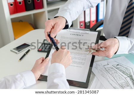 Realtor giving a pen to his client to sign the real estate contract in real estate agency