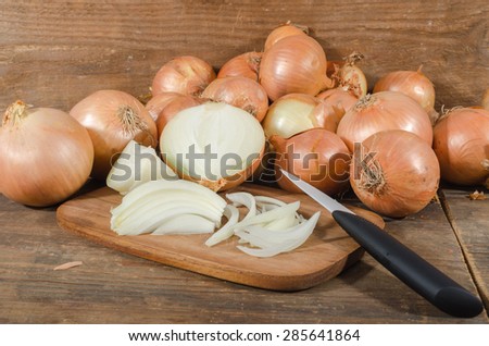 Fresh sliced and whole onions on wooden background