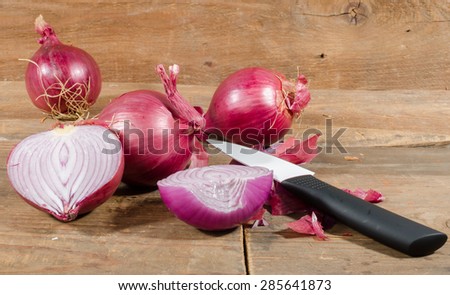 Fresh half and whole red onions on wooden background