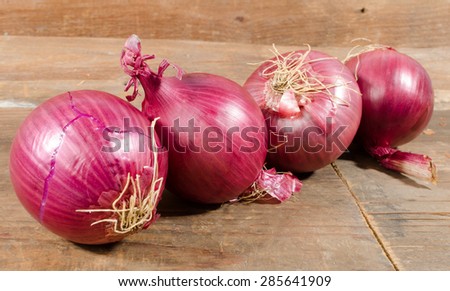 Fresh bulbs of red onions on wooden background