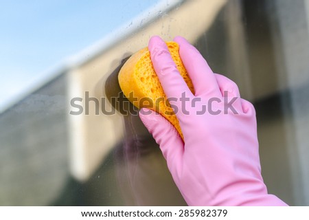 Gloved hand cleaning window, closeup