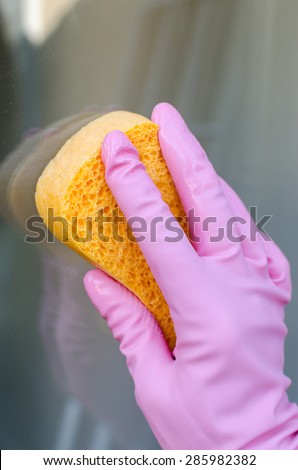 Gloved hand cleaning window, closeup