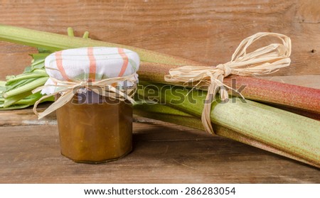 Rhubarb stalks with rhubarb jam jar on wooden background