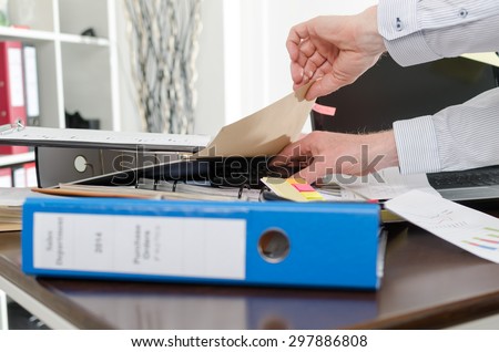Businessman looking for his phone on his messy desk