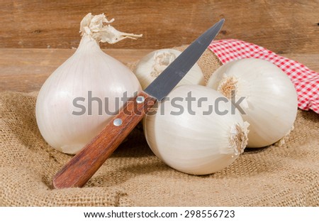 White onions with a knife on burlap