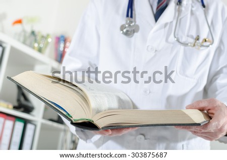 Doctor doing research in a medical book at office