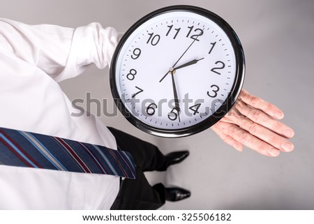 Businessman standing, looking at his large watch