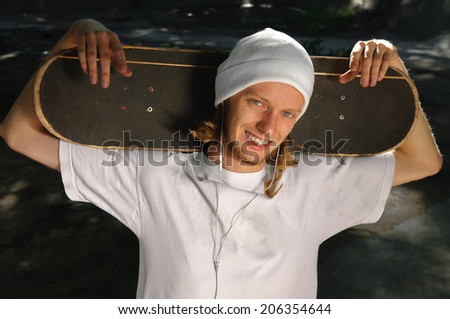 Happy guy with skateboard on his shoulders