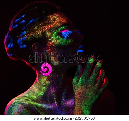 Red  light contour on the sensual woman with fluorescent paint makeup. Model looking at the side. Luminescence paint. Dark background with copy space