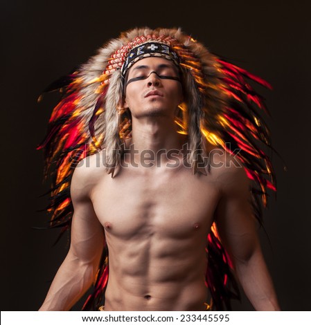 Naked indian strong man with traditional native american make up and headdress. Mixed light  studio shot