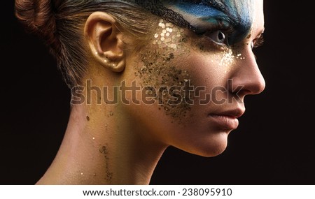 Young woman looking at the side with fantasy make up. Ususual face art studio shot. Copyspace. High resolution