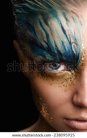Young woman looking at camera with fantasy make up. Cose up Ususual face art studio shot. Half head