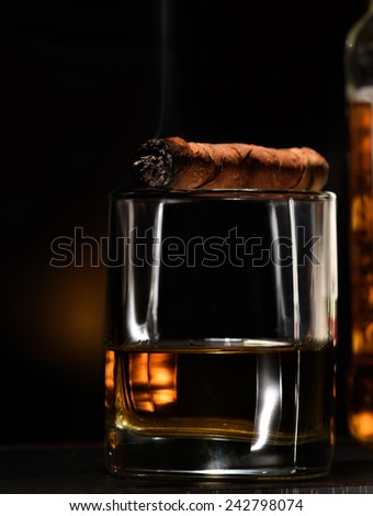 Luxury still life with cognac and cigar on a dark background. Close up shot with copyspace