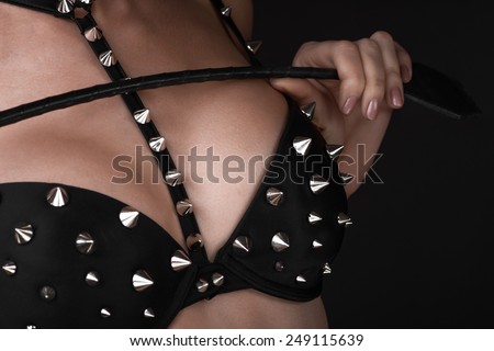 Sexy girl in black spiked bra play with lash. Bdsm concept no face. Copyspace
