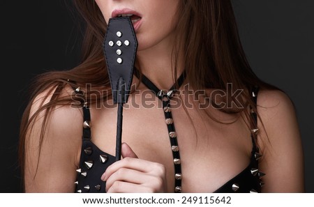 Sexy girl in black spiked bra play with lash. Bdsm concept no face. Copyspace