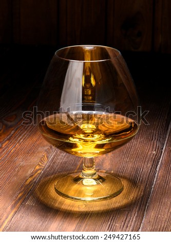 Luxury still life with glass of cognac, on a wood background. Front view with copyspace. Close up shot. High resolution