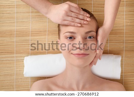 Beautiful young woman getting relaxing head  massage in the spa salon. Top view high resolution shot. Smiling model