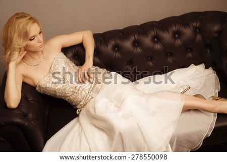 Luxury blonde woman posing on sofa. Top view