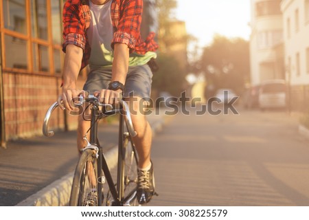 Close up hipster on bike in the city at sunset. Shot with sunflare and without face.