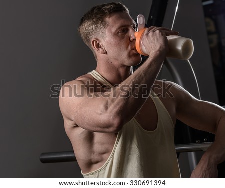 Athlete man drinking protein in gym. Copyspace