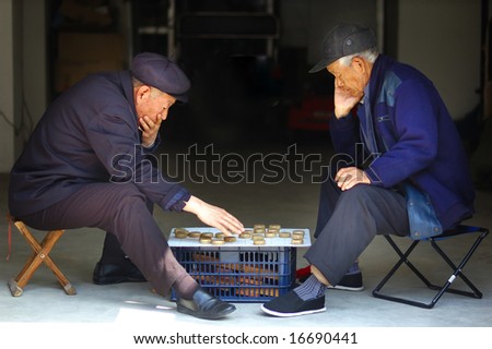 Two old Chinese man play Xiangqi. Xiangqi, or Chinese Chess, is an extremely popular game in China.