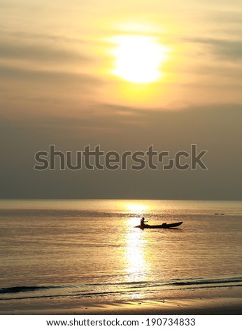 Sunset above sea with people in kayak