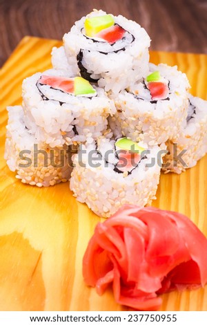 inside out sushi roll with salmon and avocado on wooden background