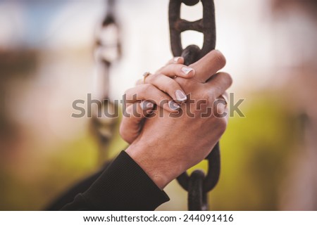 couple holding hand together on metal chain