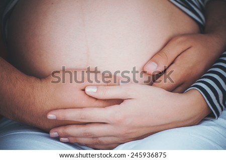 men holds hands on belly of pregrant women no face