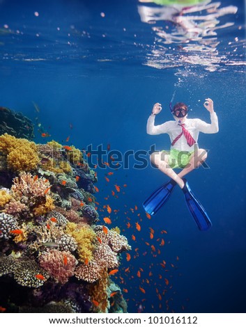 White collar worker man meditating underwater close to coral water with red tie and white shirt
