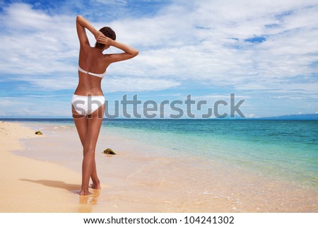 Tanned woman\'s back relaxing on the sandy beach