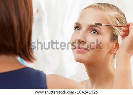 Portrait of a model having separating and curling lashes with mascara brush - professional makeup artist working