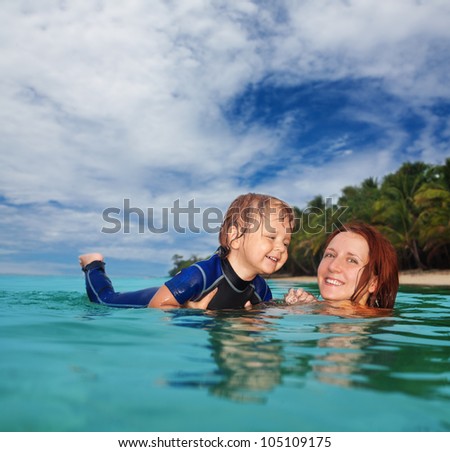 Mother teaches little boy to swim in the sea. Two years old boy wears wet suit