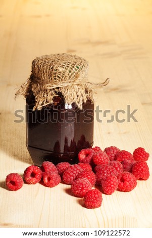 jelly jar on wooden table and bunch of rasberries