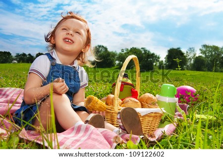 funny red girl sitting in the park with picnic basket