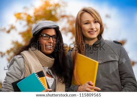 two happy girls with books in park