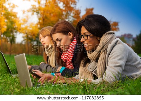 three students browsing in autumn park