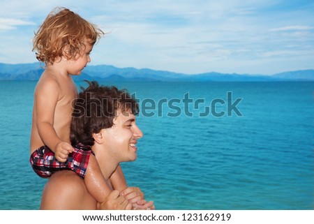 Daddy carry happy  kid on shoulders on seashore