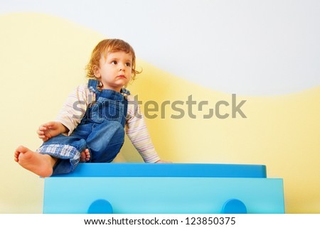 Happy kid sitting on the blue cabinet
