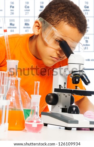 black ten years old boy on chemistry class using microscope