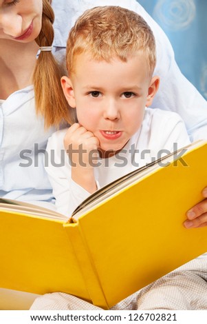 Five years old boy bored and prank with face expression while his mother trying to teach him to read