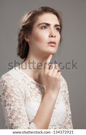 Beauty portrait of calm woman touching chin with hand on gray