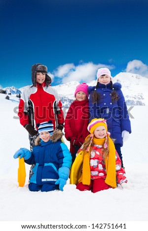 Group of five friends kids boys and girls standing together outside in snow