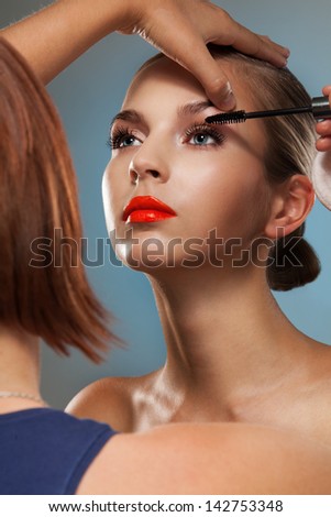 Make up artist at work, correcting eye lashes preparing motel to beauty photo session